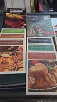 Photo showing 6 Better Homes and Gardens Encyclopedia of Cooking volumes and Woman's Day Encyclopedia of Cookery volumes with colorful food photographic covers.