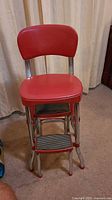 Front view of the red vinyl kitchen chair with attached steps and chrome legs.