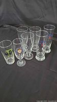Front view of six assorted beer glasses showing various brands including Michelob Ultra, Beaus, and Blanche Chambly