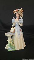 Front view of the Victorian lady ceramic figurine showing detailed dress, hat, birds, and birdbath