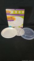 Microwave accessory set displayed with original box. Includes tray, defrosting grid, and cover all made of white or translucent plastic suitable for microwave use.