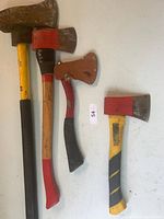 Set of four axes ranging in size from small hand axes to larger splitting axes, showing wear and paint on handles.