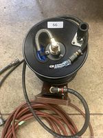 Front view of black Campbell Hausfeld air hose reel with attached hoses and fittings on concrete floor.