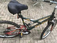 Side view showing frame, saddle, pedals, rear shock, and rear tire with knobby tread.