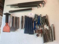 Overview of assorted chisels and punches arranged on a white table