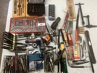 Overview photo showing a large assortment of machinist tools including taps, dies, punches, and accessories spread on floor surface
