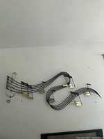Full view of both black metal music staffs with attached gold-tone musical notes and a treble clef mounted on wall.