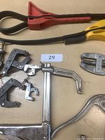 Top view of lot showing metal clamps, gear puller, and rubber strap wrenches on a table with lot number card