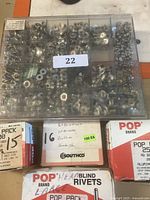 Top view of plastic organizer box filled with various metal rivets and washers with a lot sticker on top