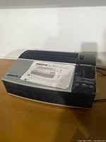 Front side view of Oreck XL air purifier showing buttons and vent design with manual on top.