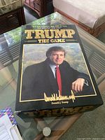 Photo of the game box with Donald Trump's portrait and the game title in gold foil.
