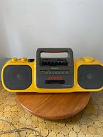 Front view showing yellow Sony Sports boom box, speakers, control panel, and tape deck.