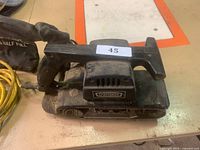Front left angle of black Craftsman belt sander showing handle, sanding belt, and general wear.