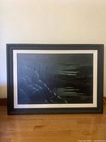 Front view of the framed dark painting showing the moody rocky landscape scene.