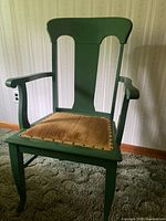 Front-facing view of the vintage green lacquered farmhouse style armchair showing the seat cushion and armrests.