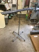 Full view of the vintage adjustable saw horse stand with wooden top and metal base