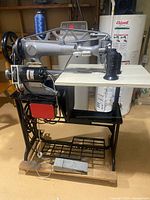 Full view of Singer sewing machine mounted on treadle stand with motor and drawer