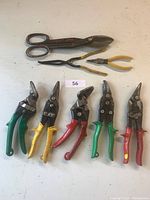 Full set of 8 vintage Swiss made sheet metal cutting tools laid out on a surface, showing various grip colors and blade types.