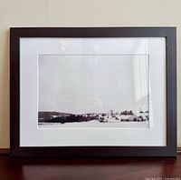 Front view of framed black and white winter landscape photograph in black frame with white mat