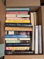 Box containing stacked hardcover novels with visible titles