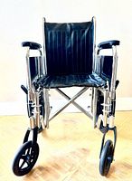 Front angle view showing seat, backrest, armrests, footrests and front caster wheel