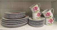Stacked dinner plates, side plates, teacups, saucers on shelf