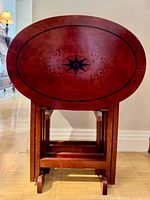 Front view of stacked oval TV trays on stand showing compass star inlay