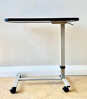 Side view showing height-adjustable column, tabletop, and castered base