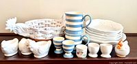 Group image showing all 17 ceramic pieces: serving bowl, small bowls, chicken fruit bowl, variety of egg cups, striped mugs