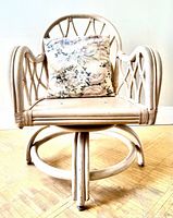 front view of off-white rattan swivel chair with floral pillow