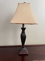Full view of painted wood table lamp with fabric shade on wooden surface