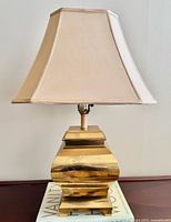 Full view of brass table lamp with shade on wooden surface