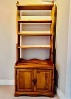 Front view of pine wall unit showing three shelves and two-door cupboard