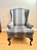 Front view of one grey striped silk wingback chair showing upholstery pattern and wooden cabriole legs