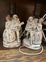 Front view of two matching porcelain courting-couple lamps with wiring visible