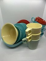 Overall view of assorted coloured Melmac dishes, plates, bowls, mugs