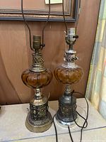 Front view of both amber glass lamps showing bases, fonts, harps and cords