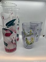 Stacked tall calla lily tumblers beside stacked shorter floral tumblers