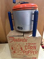 Corn popper on top of original box, front view