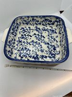 Top view of square blue spongeware casserole showing interior pattern and ruler indicating approx 8 in