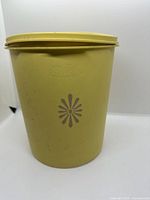 Side view of one yellow Servalier canister showing floral motif