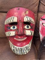 Front of carved wood mask with painted stripes
