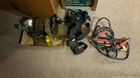 Overall lot showing three round lights in cardboard tray, four black straps with buckles, and one set of booster cables
