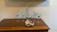 Full set on surface: decanter with stopper centered, four goblets flanking