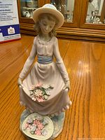 Front view of figurine showing girl holding flowers and dish at base