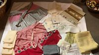 Overview of entire lot spread on white surface showing aprons, napkins, towels, runner and fabric pieces