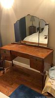 Front view of vanity showing burl top, five drawers, cabriole legs, and tri-fold mirror