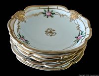 Stack of five matching scalloped porcelain sauce dishes with gold gilt rim and rose motif