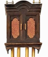 Front view of wooden chime clock housing showing doors with copper lattice and brass finials