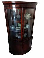Full view of Drexel mahogany bow-front corner cabinet showing glazed doors, shelves, lower compartment